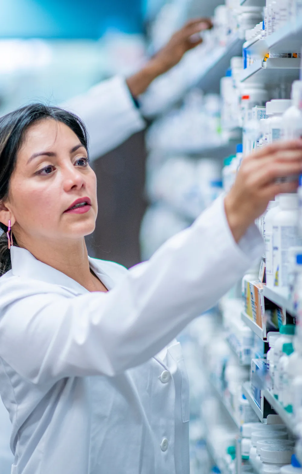 Apothekerin und Kollegin beim Einräumen von Medikamenten in den Regalen einer Apotheke
